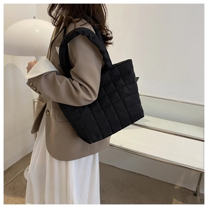 Quilted black tote bag showing the side-rear view on a model with neutral background