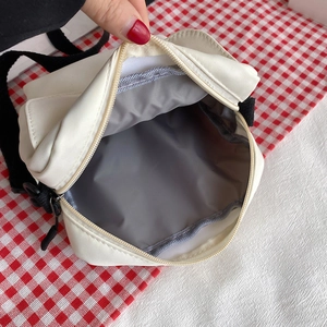 Minimalist white nylon crossbody bag with black strap showing interior storage and zip closure