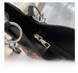 Gros plan sur la fermeture éclair argentée et le cuir noir texturé du sac fourre-tout