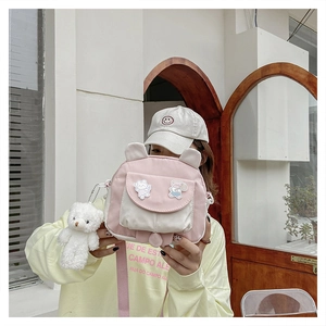 Detail of cute rabbit-ear crossbody bag featuring a plush bear charm and cartoon badges