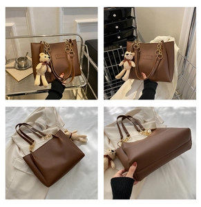Detail of dark brown PU leather tote bag with gold chain strap and bear charm