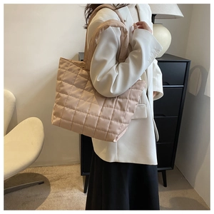 Side view of beige quilted tote bag worn over shoulder for daily commute style