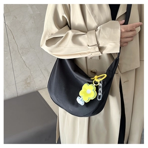 Détail du sac hobo noir avec pendentif fleur jaune et chaîne décorative en acrylique