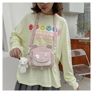 Detail of cute canvas crossbody bag with bunny ears, bear charm, and adjustable strap