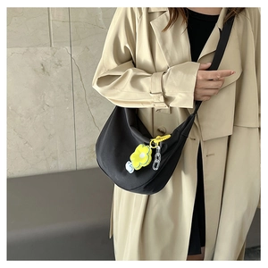 Détail du sac demi-lune noir avec breloque fleur jaune et bandoulière en chaîne acrylique