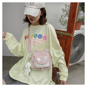 Detail of cute rabbit ear crossbody bag with plush bear charm and pastel pink straps