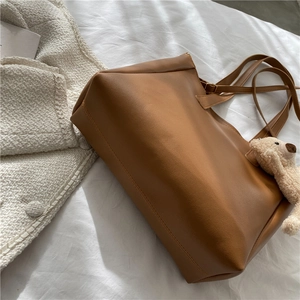 Brown soft leather tote bag for women with a cute plush bear charm for daily use
