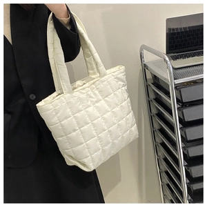 Detail of white quilted tote bag showing padded stitching and spacious nylon texture