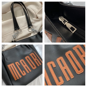 Vue détaillée du cabas en cuir noir avec lettres orange et bandoulière en chaîne