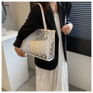 Detail of semi-transparent tote bag with white M-pattern print and beige straps