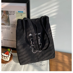 Dettaglio di una borsa tote in velluto a coste nera con ricamo a forma di orso cartone