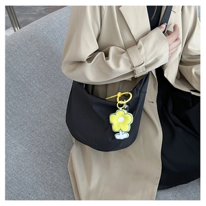 Détail du sac bandoulière noir en demi-lune avec breloque fleur jaune sur mannequin