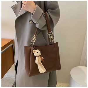 Detail of dark brown PU leather tote with gold chain and beige knit bear charm