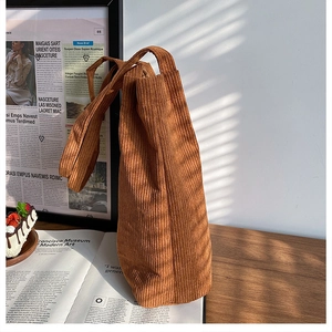 Texture dettagliata della borsa tote in velluto a coste marrone su base in legno