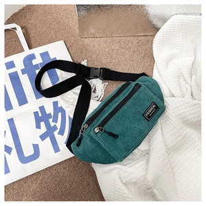 Detail of dark green corduroy waist bag showing vertical texture and dual zipper pockets