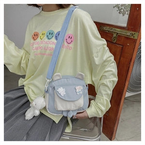 Detail of light blue crossbody bag with 3D animal ears and white plush bear charm