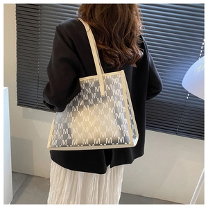Detail showing high-capacity PU tote bag with repeating M-letter pattern on textured surface