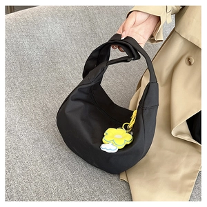 Gros plan du sac hobo croissant en nylon noir avec un charmant pendentif tournesol