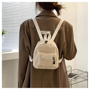Detailed view of a mini beige faux shearling backpack worn over a brown blazer
