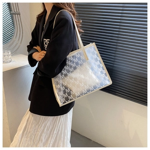 Detail of transparent tote bag with white M-letter print and faux leather shoulder straps