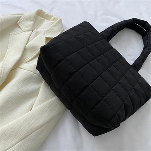 Large black quilted tote bag with padded texture shown at 45-degree angle on white fabric