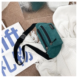 Macro view of dark green corduroy waist bag showing double zippers and brand label