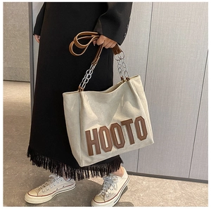 Détail du sac cabas en toile blanc cassé avec écusson HOOTO et bandoulière en chaîne