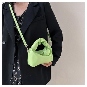 Dettaglio della borsa verde fluo con manico a pieghe e tracolla rimovibile in metallo