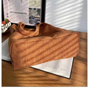 Dettaglio ravvicinato della borsa tote in velluto a coste marrone con ricamo bianco