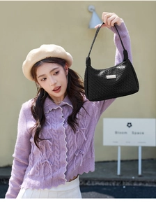 Détail du sac hobo noir à texture tressée avec plaque argentée porté par un mannequin stylé