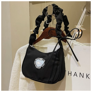 Details der schwarzen Schultertasche mit blauem Herz-Patch und Wal-Print-Design