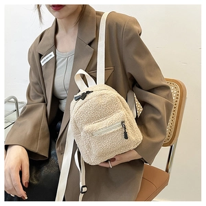 Close-up of fluffy beige faux shearling mini backpack with textured zipper pocket