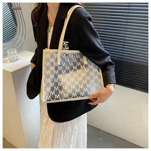 Detail of semi-transparent PU tote bag with white letter M pattern and leather straps
