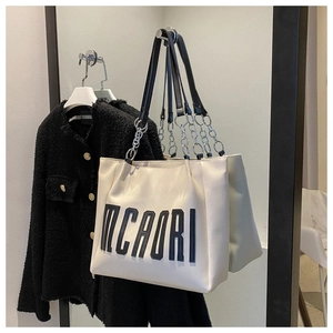 Détail du grand sac cabas avec lettrage MCAORI et bretelles en chaîne de cuir noir