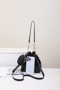Detail of black drawstring bucket bag set with mini coin purse and gold chain strap
