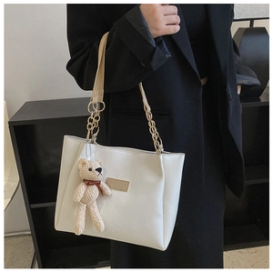 Detail of off-white PU leather tote bag with gold chain strap and cute bear charm pendant
