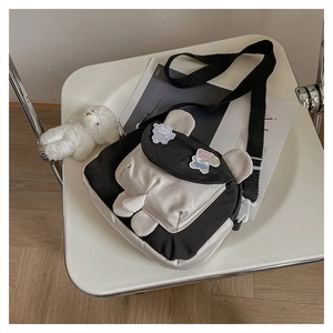 Close-up of black and white canvas crossbody bag with bear ears and cartoon badges