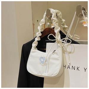 Detailansicht der weißen Schultertasche mit Faltenriemen und Herz-Wal-Aufnäher