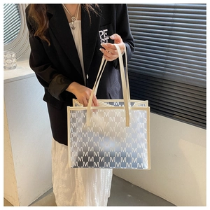 Macro view of frosted translucent tote bag with M pattern and cream leather handles