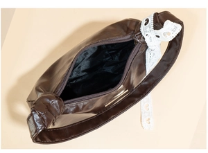 Detail view of brown glossy PU leather underarm bag with zipper and lace decoration