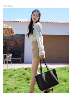 Outdoor shot of a woman carrying a large black soft leather tote bag on a lawn