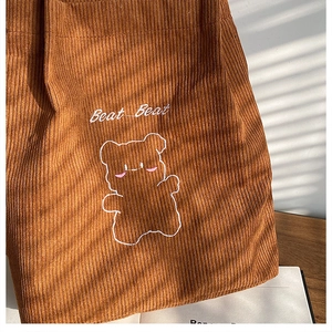Dettaglio della borsa in velluto a coste marrone con ricamo di orso e testo Beat Beat