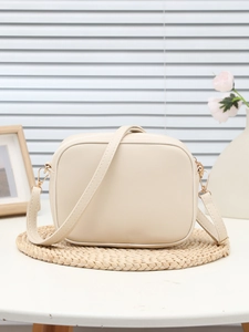 Dettaglio di una borsa a tracolla crema con fibbie in metallo dorato e pelle sintetica fine