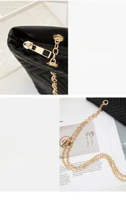 Close-up of golden zipper puller and elegant chain strap on V-quilted black tote bag