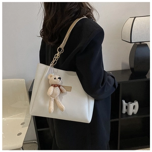 Detail of cream PU tote bag featuring a cute teddy bear charm and soft shoulder strap