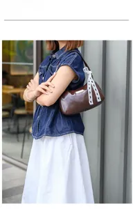 Brown faux leather underarm bag with white lace bow detail shown on a female model