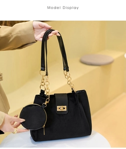 Detail of black velvet tote bag with gold twist lock, chain strap, and round coin purse