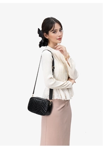 Detail of black quilted crossbody bag with adjustable wide strap and gold hardware