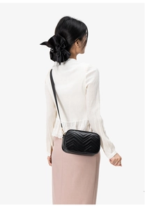 Detailed view of black leather crossbody bag featuring classic chevron quilted pattern