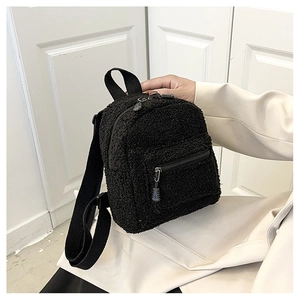Detail of black faux shearling backpack showing soft lamb wool texture and zipper pocket